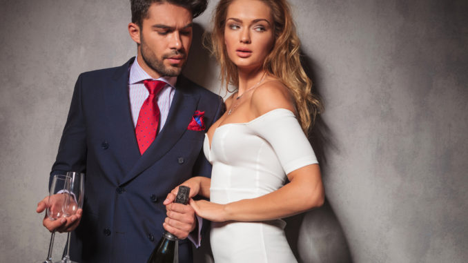 Side view of a hot fashion couple with champagne and glasses ready to celebrate