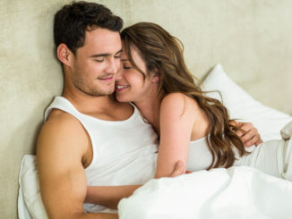 Romantic couple cuddling on bed in bedroom