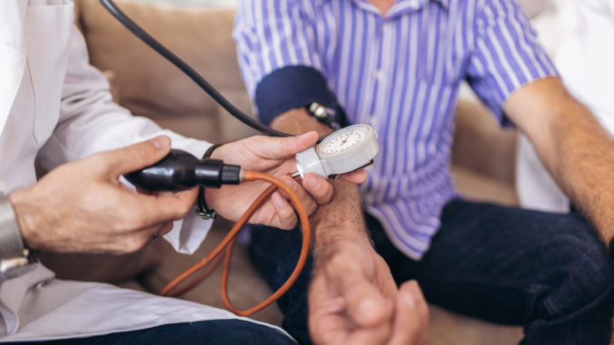 Doctor checking old man patient arterial blood pressure. Health care.