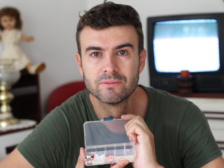 Unhealthy looking man holding pillbox.