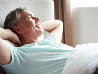 Middle Aged Man Waking Up In Bed Looking Away From Camera Smiling