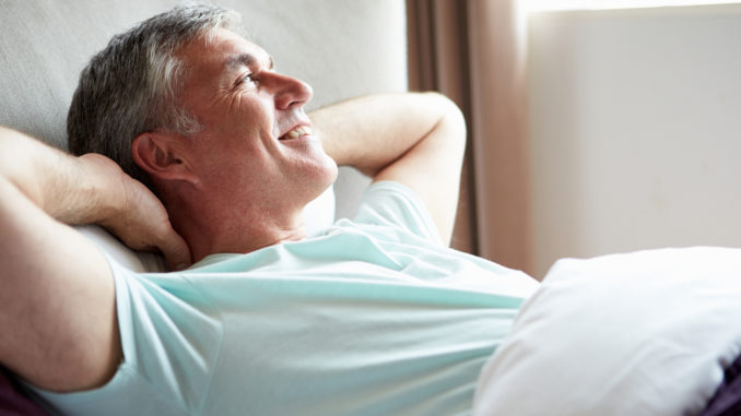 Middle Aged Man Waking Up In Bed Looking Away From Camera Smiling