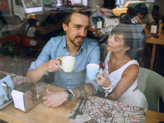 Man talking to women with cup of cappuccino while resting in cafe