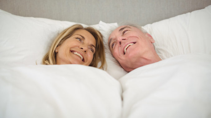 Happy senior couple lying on bed in bedroom