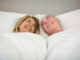 Happy senior couple lying on bed in bedroom