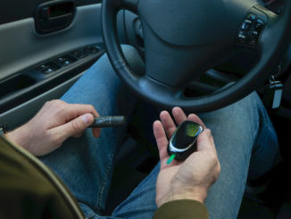 Diabetes concept. Diabetic man checking blood sugar level at car.