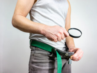 Man looking in his underwear with magnifying glass.