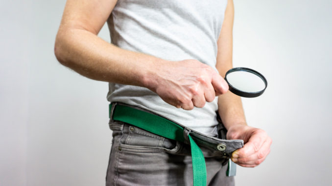 Man looking in his underwear with magnifying glass.