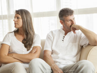 middle aged couple at home on the sofa and fighting