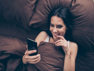 Top above high angle view close-up portrait of her she nice attractive, lovely flirt charming cute cheerful cheery girl using gadget sending photos lying in bed in room flat house indoors