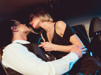 Handsome stylish men embracing fashionable young women in car