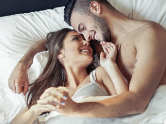 Happy romantic couple embracing in the bed