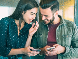 Happy young couple having fun with mobile smart phone at urban place