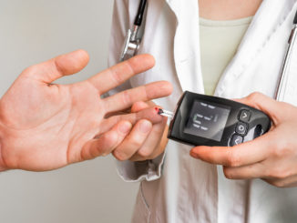 Doctor checking blood sugar level with glucometer