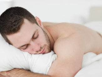 Man lying on his belly while sleeping in his bedroom