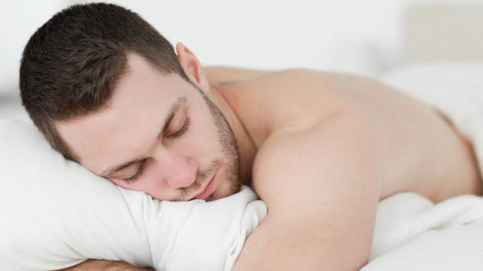 Man lying on his belly while sleeping in his bedroom