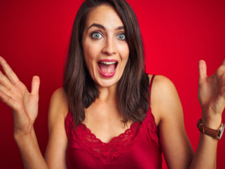 Young beautiful woman wearing lingerie over red isolated background celebrating crazy and amazed for success with arms raised and open eyes screaming excited.