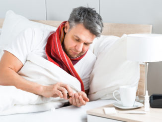 Mature Sick Man Lying On Bed Having Medicine