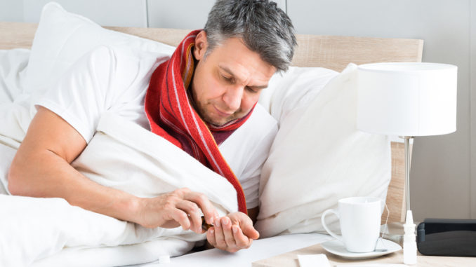 Mature Sick Man Lying On Bed Having Medicine