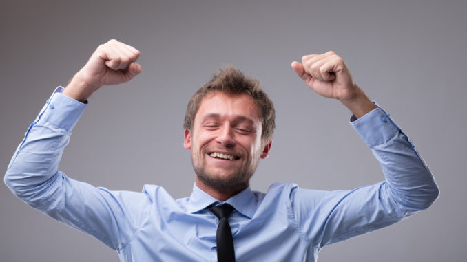 Jubilant happy man cheering and punching the air with his fists as he celebrates a victory or success