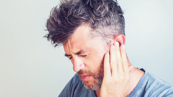 Man with earache is holding his aching ear body pain concept