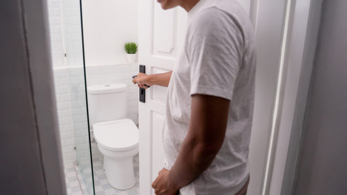 Man hold his genitals to pee and open the toilet door