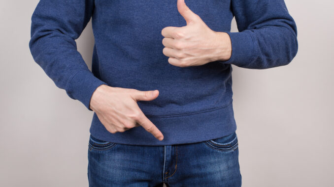 Cropped close-up photo of satisfied confident cool guy demonstrating pointing on his he organ in pants trousers isolated grey background.
