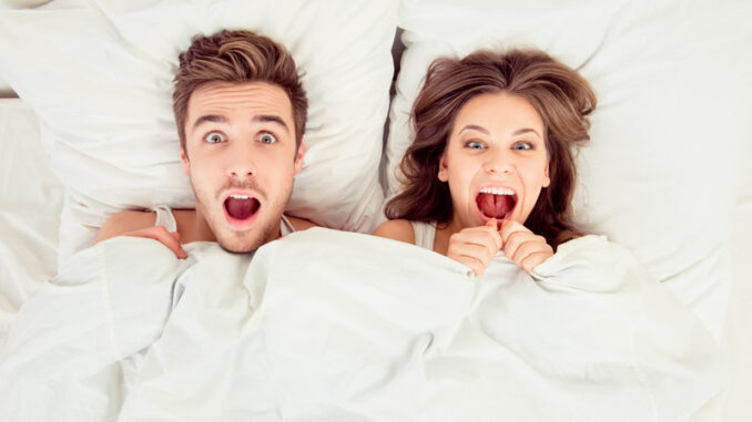 Surprised funny couple in love lying in the bed.