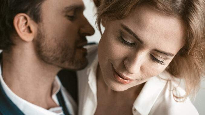 Man going to kiss female neck