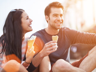 Photo of a romantic couple eating ice cream at park at sunset