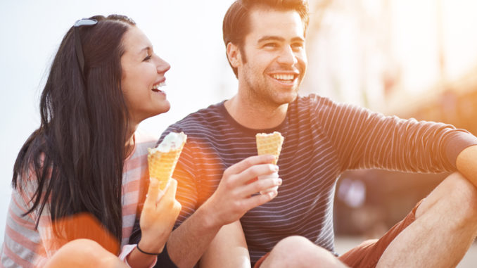 Photo of a romantic couple eating ice cream at park at sunset