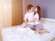 Happy young attractive couple hugging on bed in the bedroom