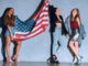 multicultural young women with american flag against concrete wall