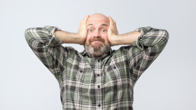 Tensed mature european man covering ears