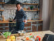 Cheerful man stand at stove and cook food in kitchen.