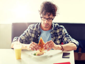 happy man eating sandwich at cafe for lunch