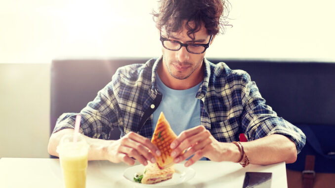 happy man eating sandwich at cafe for lunch