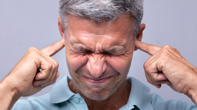 Close-up Of A Mature Man Covering His Ears With Fingers