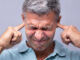 Close-up Of A Mature Man Covering His Ears With Fingers