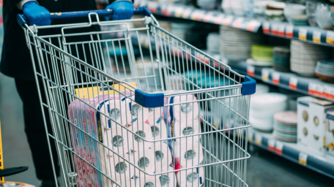 Man in protective gloves buying toilet paper in shop. Panic at coronavirus epidemic.