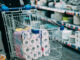 Man in protective gloves buying toilet paper in shop. Panic at coronavirus epidemic.