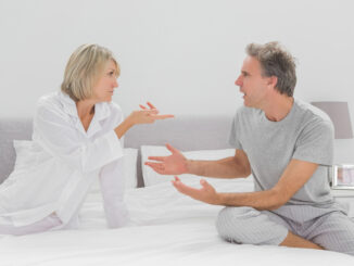 Couple arguing in bedroom sitting on bed