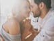 Beautiful young couple bonding and smiling while sitting in the bedroom