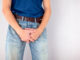 Man in jeans covers his crotch with hands