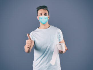 Man in medical mask holding toilet paper roll