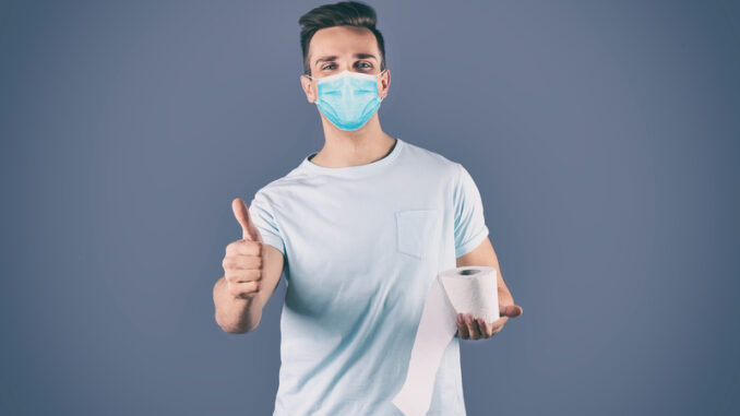 Man in medical mask holding toilet paper roll