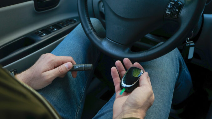 Diabetes concept. Diabetic man checking blood sugar level at car.