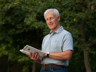 Skinny happy old man reading book in the park outdoor