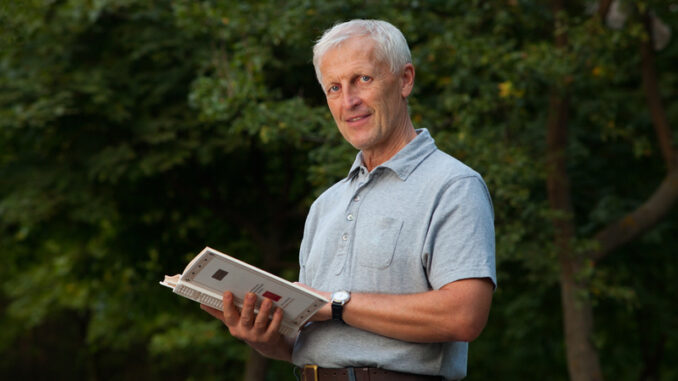 Skinny happy old man reading book in the park outdoor