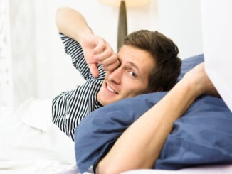 Happy man sleeping in bed alone.